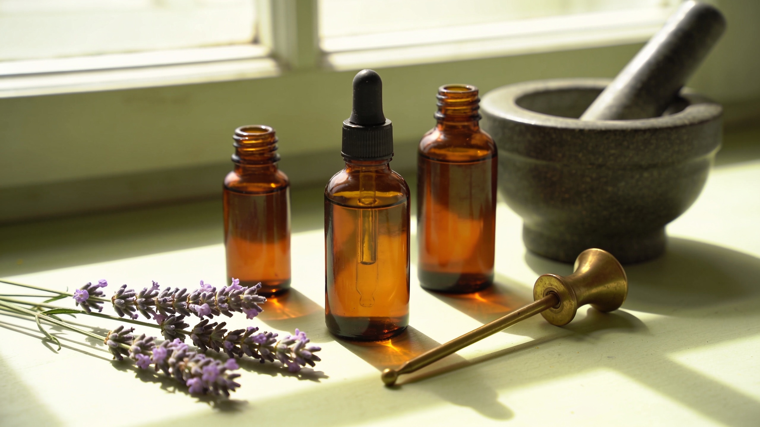 Amber dropper bottles, dried lavender and a stone mortar and pestle in soft window light