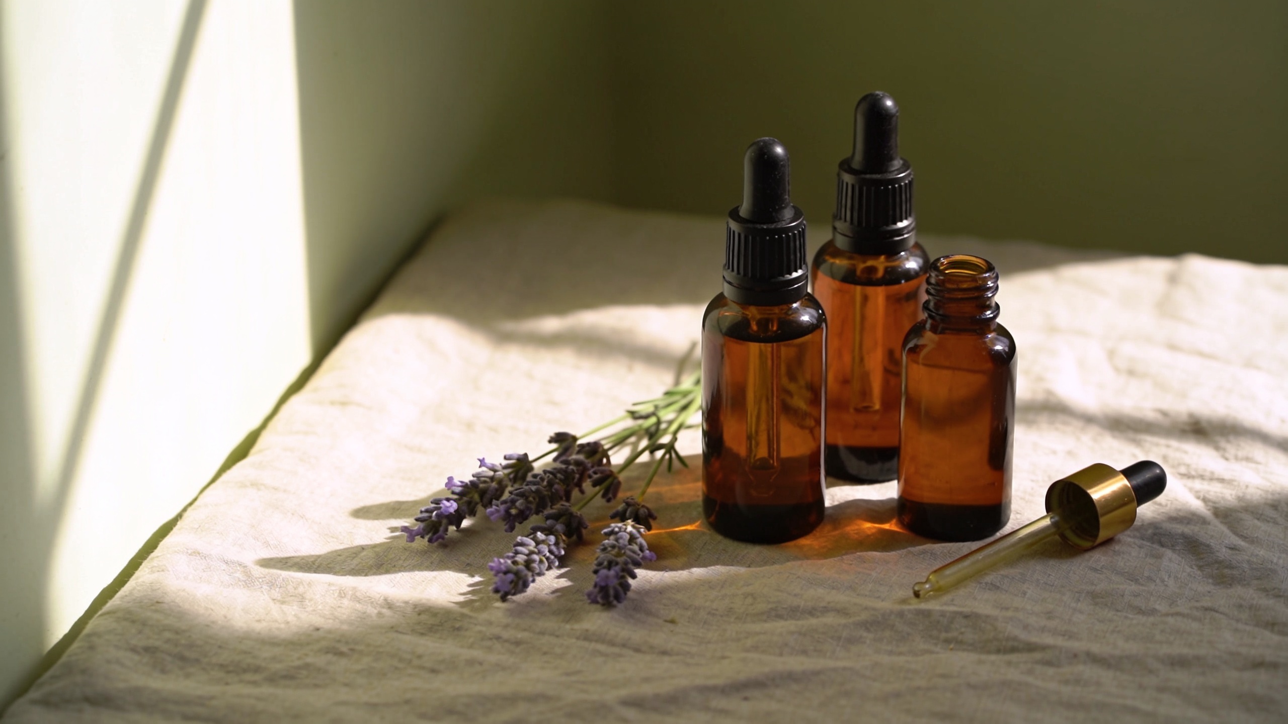 Amber essential-oil dropper bottles with fresh lavender on a windowsill